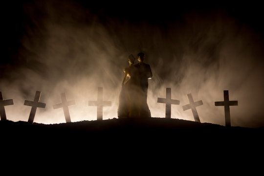 Halloween. Scary zombie bride on a night cemetery holds a pumpkin lantern.