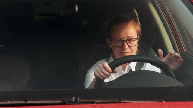 woman stands in traffic sitting behind the wheel of a car and is nervous.
