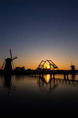 Fototapeta na wymiar Traditional Romantic Dutch Windmills and Wooden Drawbridge in Kinderdijk Village in the Netherlands. Picture Taken At Golden Hour.