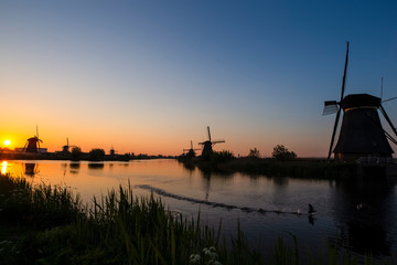 Fototapeta na wymiar Traditional Romantic Dutch Windmills and River in Kinderdijk Village in the Netherlands. Picture Taken At Golden Hour.