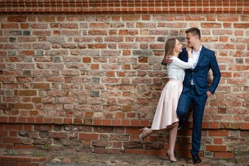 Portrait of Smiling Happy Couple Embracing Together Against Brick Wall.