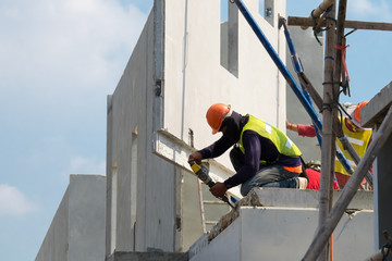 Construction worker use electric drill Drilling concrete wall in construction area, Precast house construction.