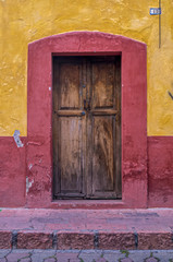 old wooden door and wall on a house yellow and red in mexico village old town
