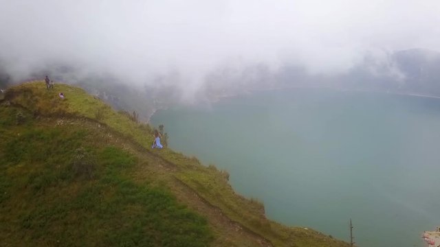 A beautiful woman runs along the rim of a volcano and cone at Quilotoa, Ecuador.