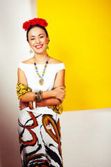 young pretty mexican woman smiling happy on yellow background, lifestyle people concept