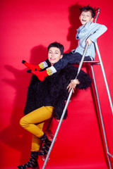 pretty young mother with little son on ladder on red background posing cheerful happy smiling, lifestyle people concept