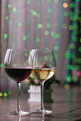 Two glasses of wine white and red standing on a table. Colorful bokeh. Wine tastings, wine tour. Cold toning. Concept alcoholic drinks. 