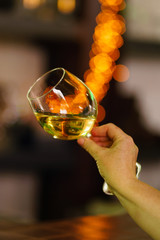 Hand sommelier holding glass of white wine. Wine-tasting. White wine concept. Wine tour. Vertical, warm toning
