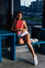 Fototapeta na wymiar Stylish happy young brunette woman wearing white shorts and sneakers holding pink cup of coffee to go.