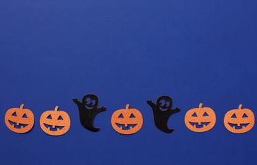 Halloween paper decorations made of ghost and pumpkins on dark blue background. Halloween concept. Minimal Flat lay Copy Space for text