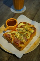 Selective focus of Pizza toasted bread with bacon and ketchup ready to eat on wooden table in restaurant, on dark background, Vertical
