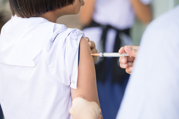 The nurse is injecting anti-tetanus  for female students in primary school in Thailand.