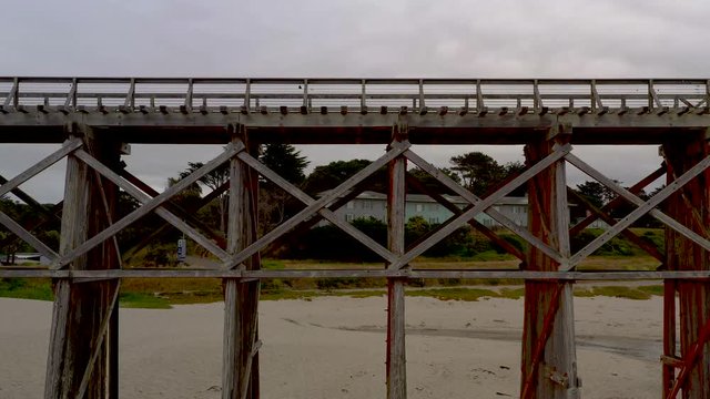 Aerial Tilt of Pudding Creek Trestle, Front Bragg, California. Drone fly down to up, historical bridge on sand beach.