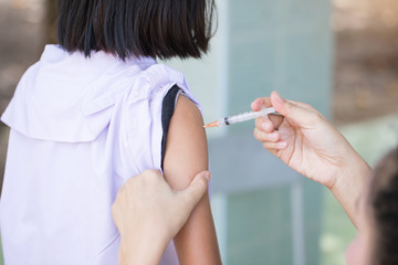 The nurse is injecting anti-tetanus  for female students in primary school in Thailand.
