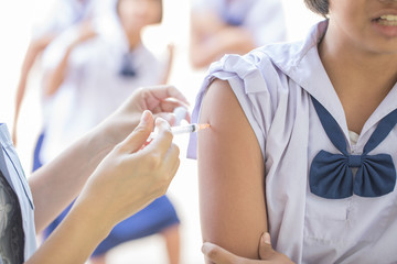The nurse is injecting anti-tetanus  for female students in primary school in Thailand.