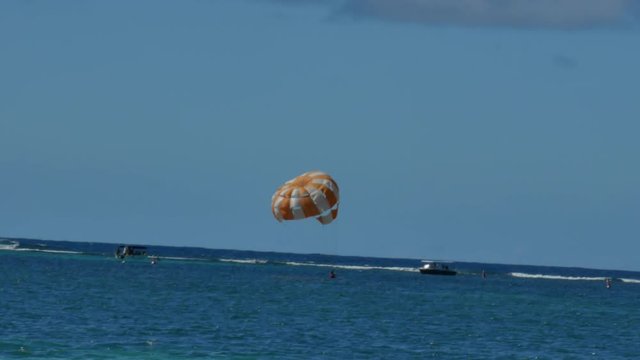 A man touching the water and going up again while practices parasailing
