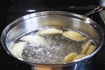 Homemade perogies (varenyky) boiling in a pot; cooking varenyky from scratch at home in the kitchen