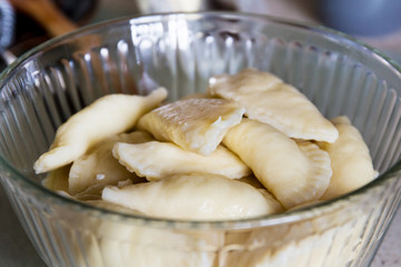 Homemade perogies (varenyky) cooked and placed in a serving bowlt; cooking varenyky from scratch at home in the kitchen