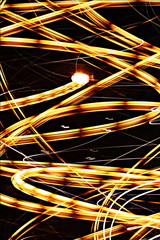Golden Web- A long exposure photograph showing a series of golden-yellow light trails photographed in a creative motion style. A photograph which can be used as a wallpaper or background/backdrop.