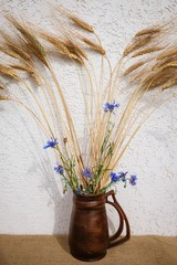 Bouquet of cornflowers and rye in a brown jug