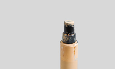Close up of used glass bottle of beige liquid concealer foundation make up isolated on gray background