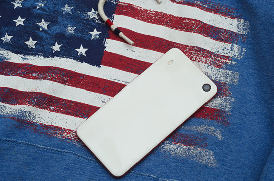 white cell phone lies on hoodie with american flag