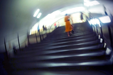 Blurred image of an underground passage in a subway. Peoples' silhouettes going up the stairs in a...