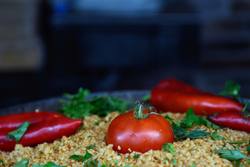 In a cast-iron skillet, pilaf decorated with red pepper, tomatoes, herbs, parsley. The concept is a holiday dinner. Holiday dish. Asian cuisine