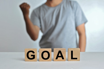 Business success for goal concept. Wooded cube block on a person standing as a background with word goal