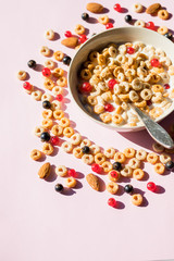 Breakfast cereals rings in a white bowl. Oatmeal, corn flakes on a pink background. Breakfast or brunch buffet in a hotel or restaurant.whole grain cereal rings with berries. Tasty and healthy