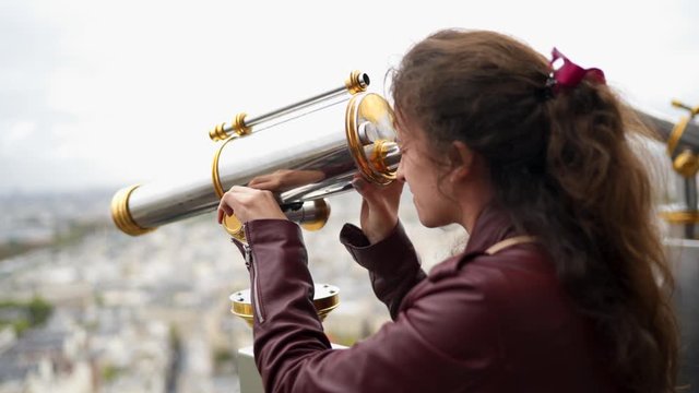 A woman looks into the Eiffel Tower telescope