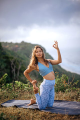 Girl practice yoga near ocean.