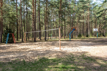 Fototapeta na wymiar swing and horizontal bars on playground in pine forest