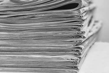 A stack of folded newspapers on the desktop in the office. Latest financial and business news in...