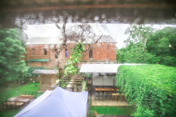 Blurred background view from the bedroom window, where there is rain outside and see the green garden fading, cool weather on holiday days.