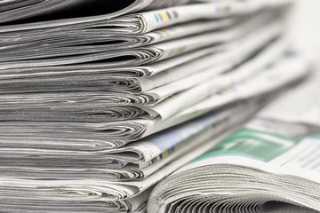 A stack of folded newspapers on the desktop in the office. Latest financial and business news in...