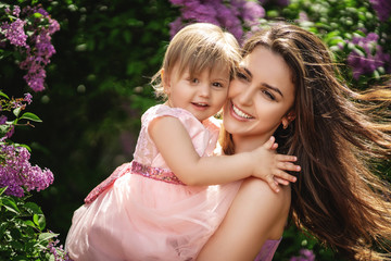 Lifestyle portrait mom and daughter in happiness at the outside in the blooming trees