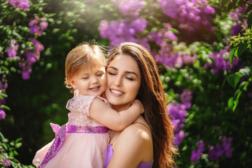 Beautiful young woman and her charming little daughter are hugging and smiling. Mother's day