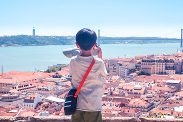 Little boy playing with a binoscope on the observation deck overlooking the old town