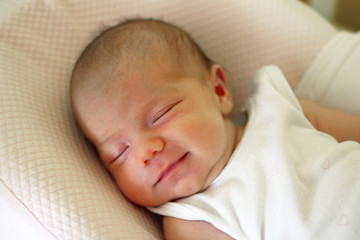 Cute newborn baby is sleeping with smile on her face.