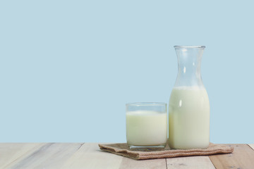A bottle of rustic milk and glass of milk on a wooden table