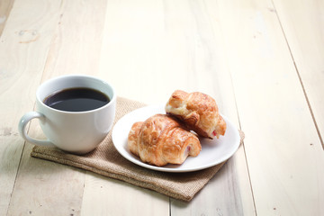 Croissant and coffee  isolated on wood table