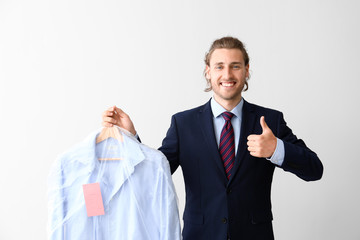 Businessman with clothes after dry-cleaning showing thumb-up on white background