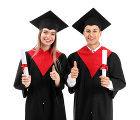 Young students in bachelor robes and with diplomas on white background