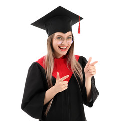 Young female student in bachelor robe pointing at something on white background