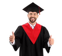 Young male student in bachelor robe showing thumb-up on white background