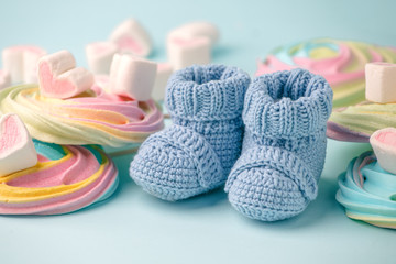 Fototapeta na wymiar baby shower decoration - it is a girl. Rainbow sweetness and knitted blue booties socks on blue background. First birthday, newborn party