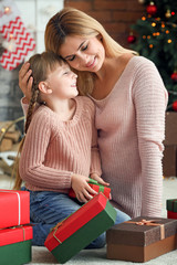 Cute little girl and her mother with Christmas gifts at home