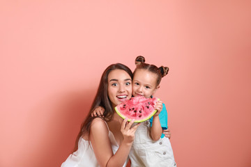 Beautiful young woman and cute little girl with fresh watermelon on color background