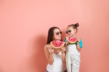Beautiful young woman and cute little girl with fresh watermelon on color background